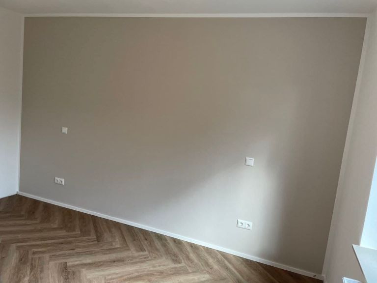 Fertige Wandfläche in warmem Greige mit gerader senkrechter Kante zur weißen Nachbarwand